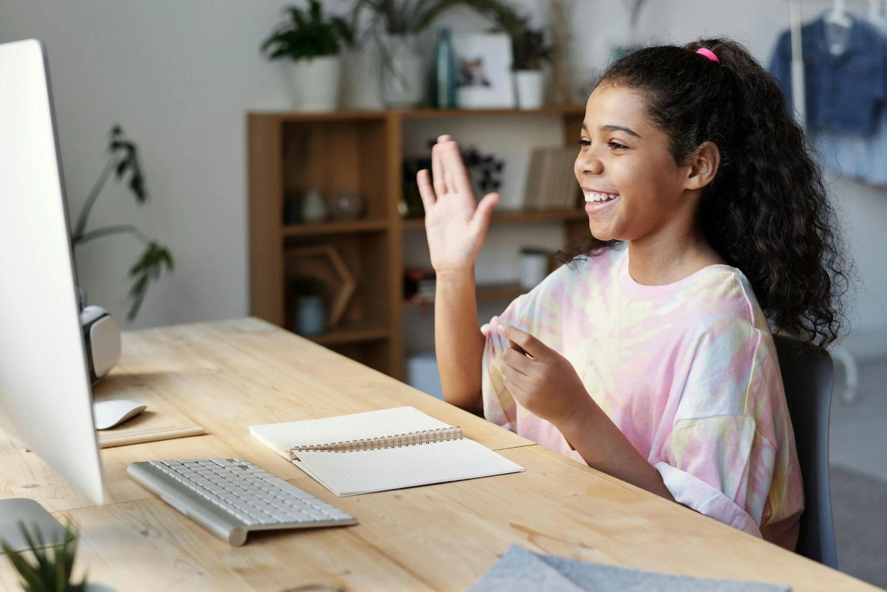 Student smiling and waving during a live online class